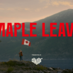 A person stands on a rocky shoreline holding a waving Canadian flag, with a scenic backdrop of a lake and mountains at sunset. The bold red text "MAPLE LEAVE" is displayed across the image, with "Presented by Canada" written below.