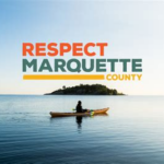 A scenic shot of a kayaker on the water in Marquette County, featuring a distant island and text overlay 'RESPECT MARQUETTE COUNTY'.