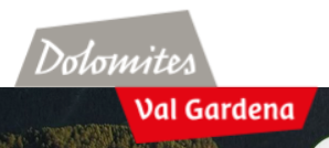 Dolomites logo with Val Gardena highlighted in red, representing the alpine destination in Northern Italy known for protected mountain landscapes.