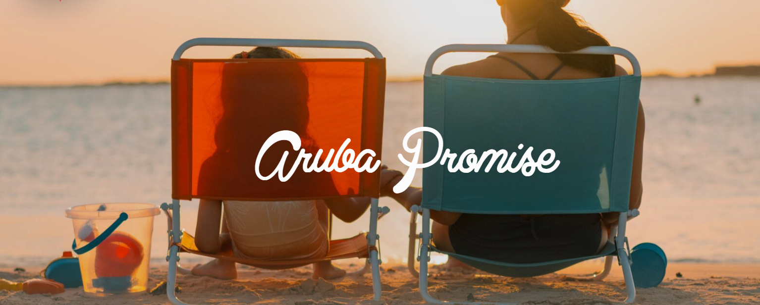 An adult and a child sit side by side in colorful beach chairs facing the ocean at sunset, with “Aruba Promise” written across the image.